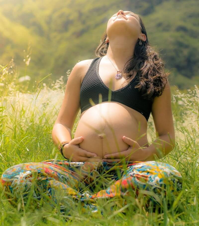 Yoga prenatal - Qué cubre el seguro médico alemán - Imagen ilustrativa, mujer embarazada haciendo Yoga en un campo