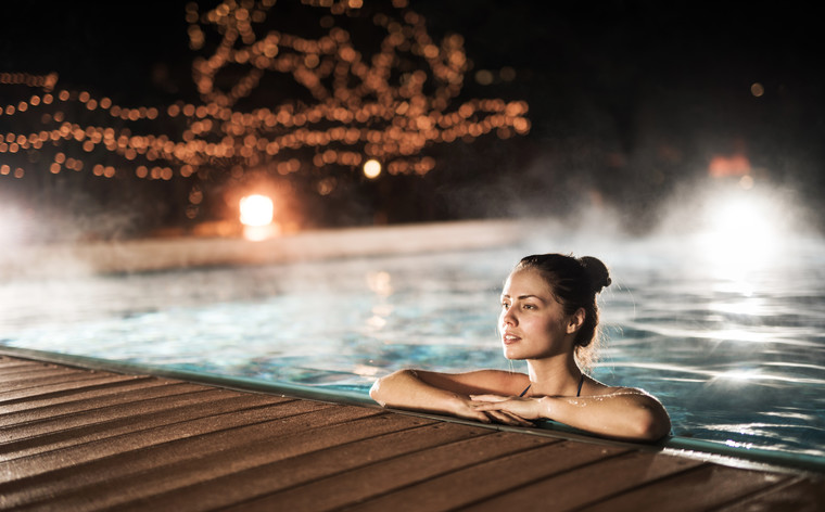 Woman spending a winter night in a heated swimming pool.