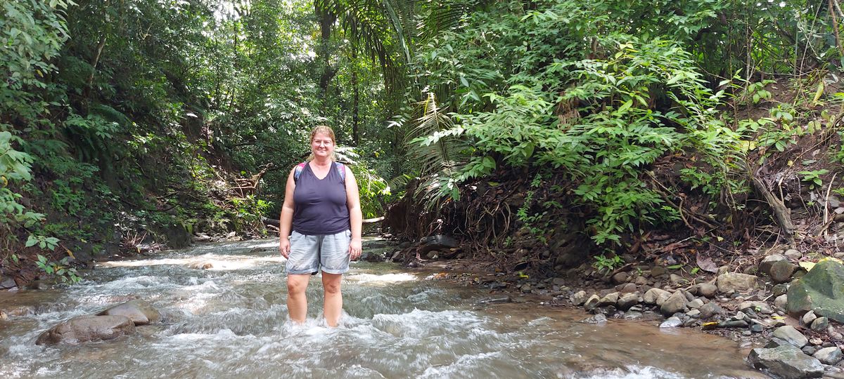 Katja steht mit beiden Füßen in einem Fluß im Dschungel in Costa Rica