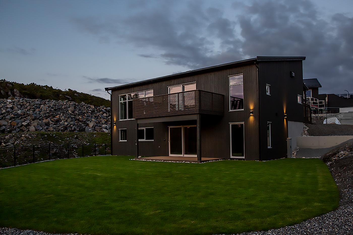 Dette er et bilde av et hus, en brun funkisbolig i solnedgang. Bildet er fotografert for Sandøy Byggservice