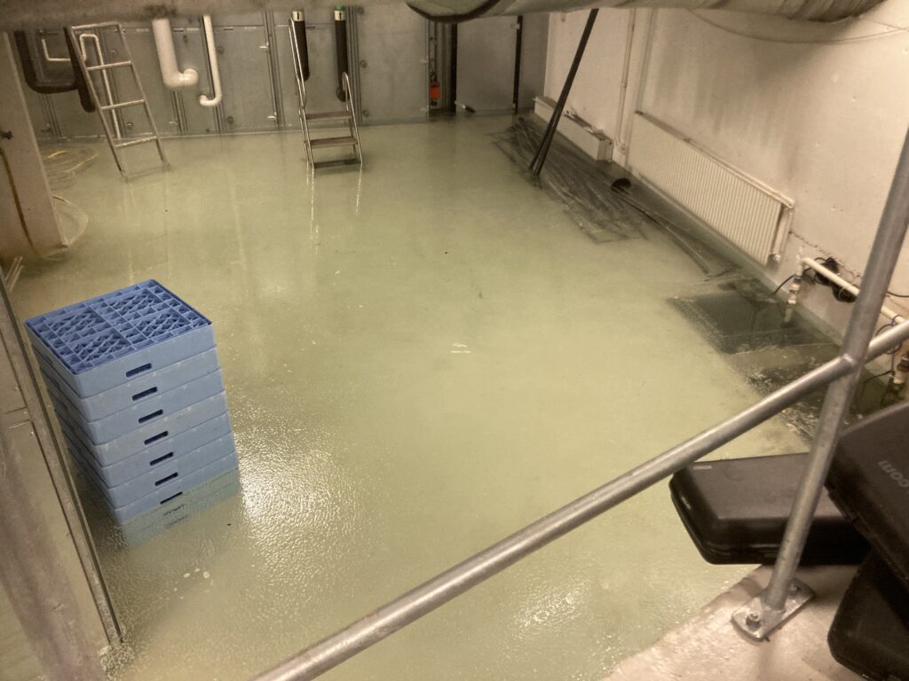 Grått industriellt rum med golvet täckt i vatten