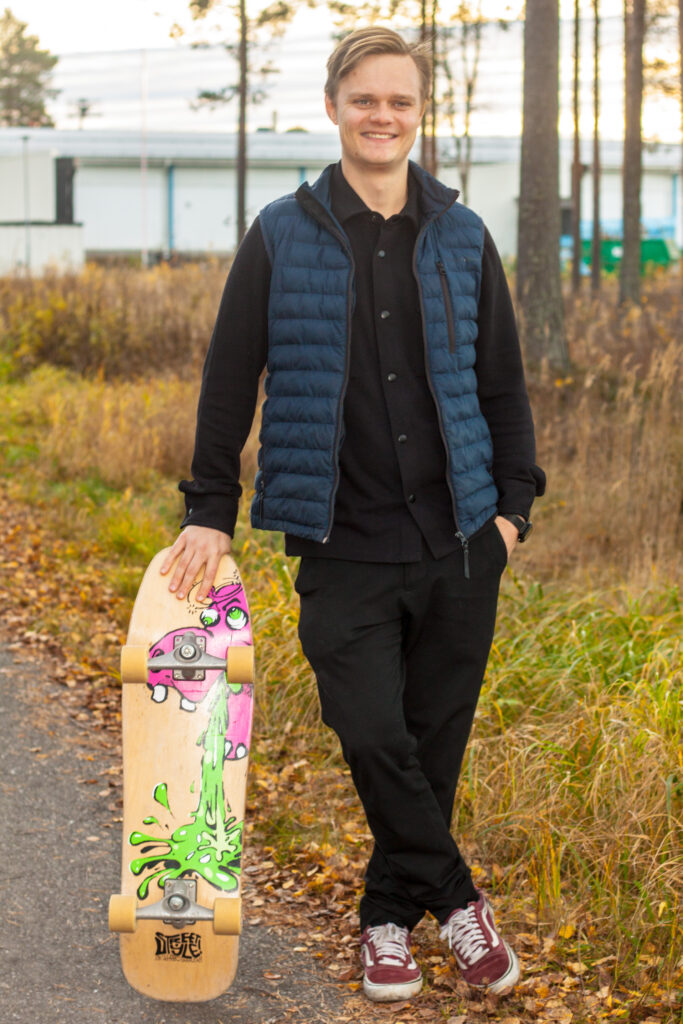 Person med väst i höstmiljö hållandes en skateboard