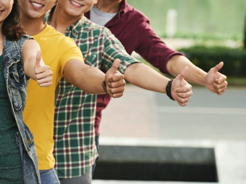 Cropped image of smiling people showing thumbs-up