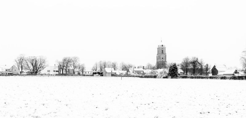 Hi-key black en white photo of snowy houses and church of Bottelare, Merelbeke, Flanders, Belgium