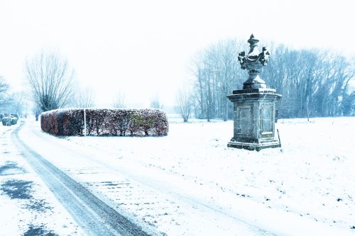 A cold snow road with old statue of the Carmelite monastery in Bottelare, Merelbeke, Flanders, Belgium