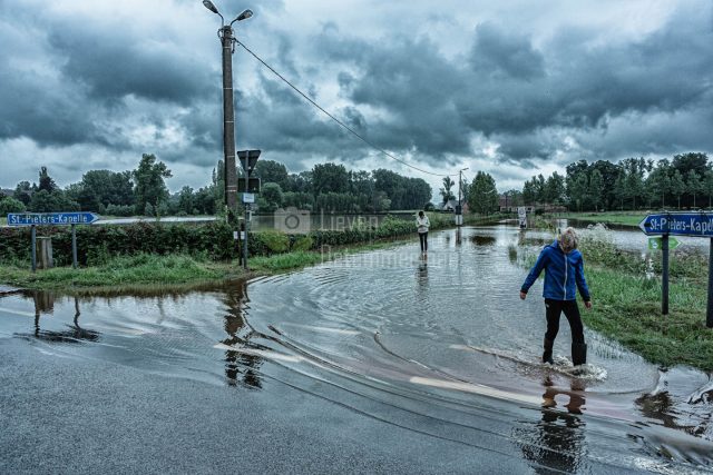 People are wading through the water of the flooded river De Mark at Herne, Flanders, Belgium