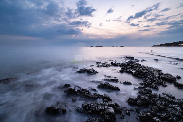 Hazy evening view with pier and swim ladder at the rocky beach of Bijela Uvala in Funtana, Croatia