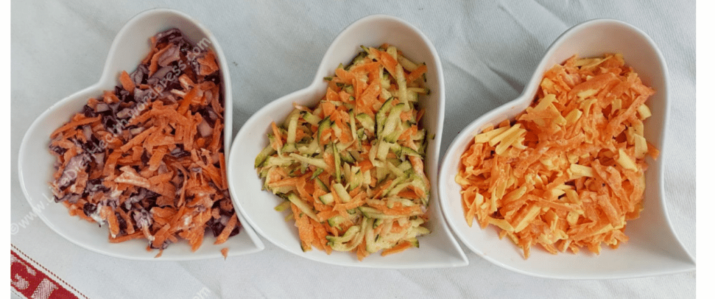 Three heart shaped bowls each with a different tye fo coleslaw in.