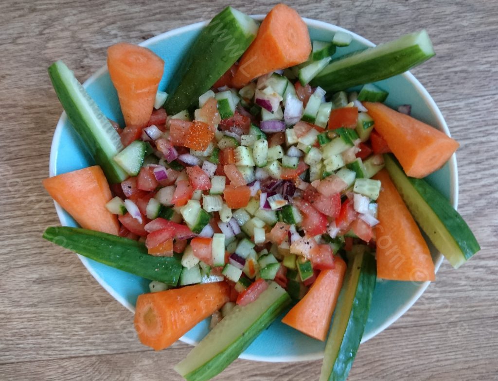 Blue dish full of diced salad with carrot and cucumber sticks around the edge. One of 5 easy summer salads.