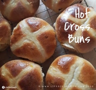 Cooked hot cross buns on a wire rack.