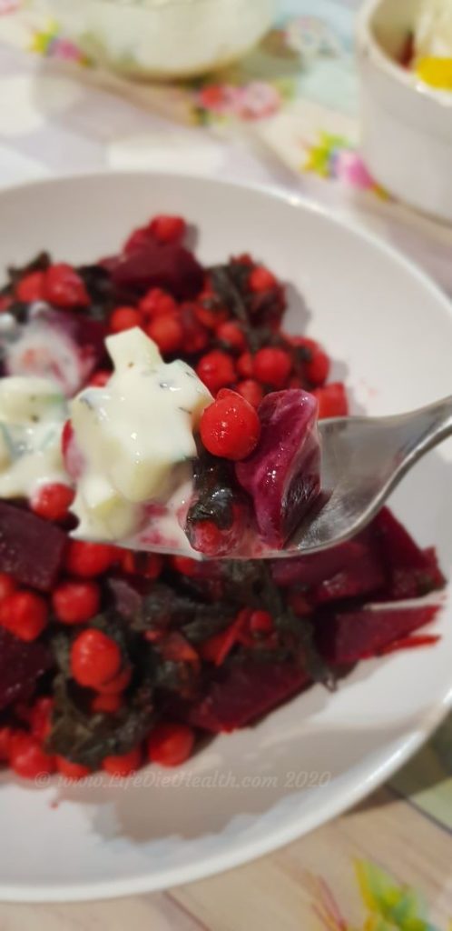 Close up forkful of beetroot, chickpea and spinach curry with raita