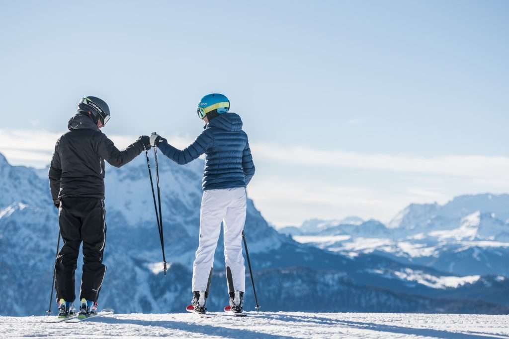 2 people cheering each other on before skiing down