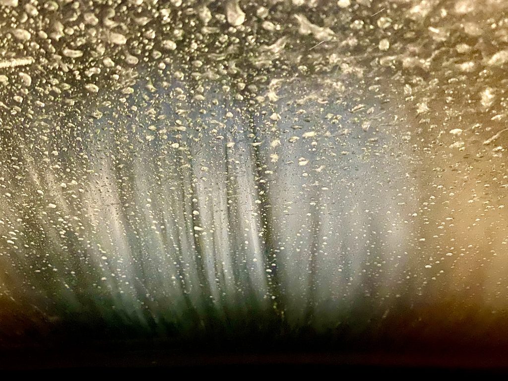 An abstract photo representing a car windshield seen from the interior of the car when the car is in the car wash. Phone photo by Mihaela Limberea.