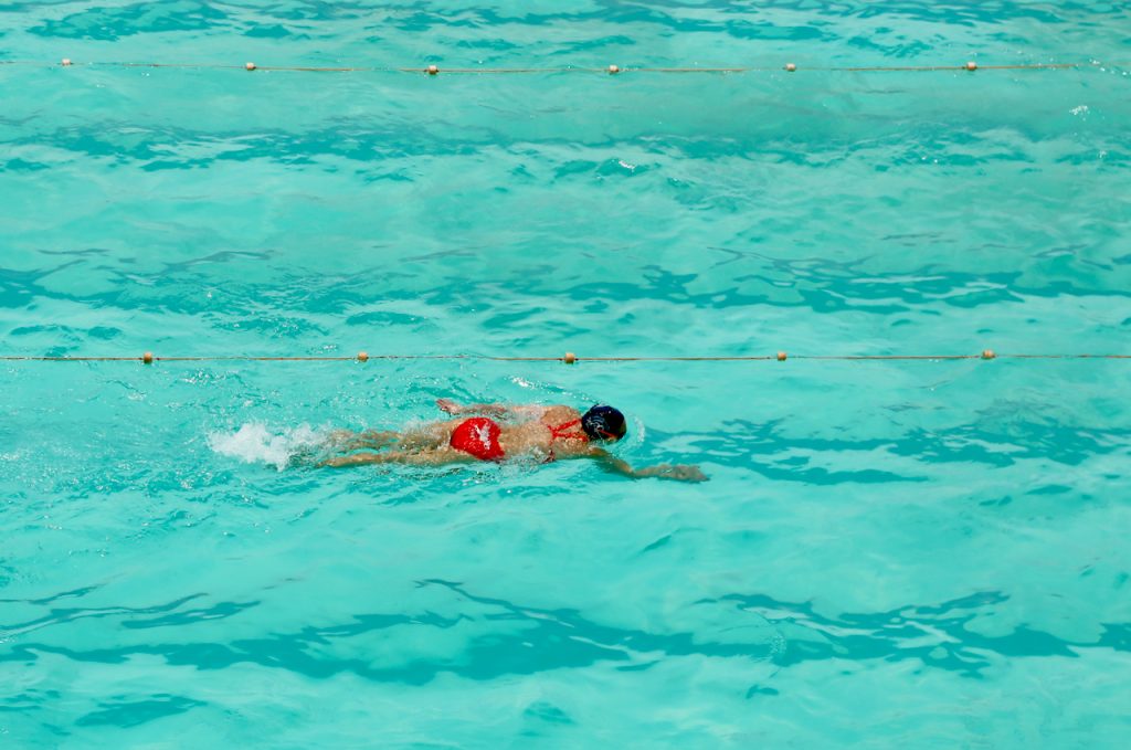 A woman in red bathing suit swims in a swimming pool at the Bondi Icebergs club in Sydney, Australia. Photo by Mihaela Limberea.