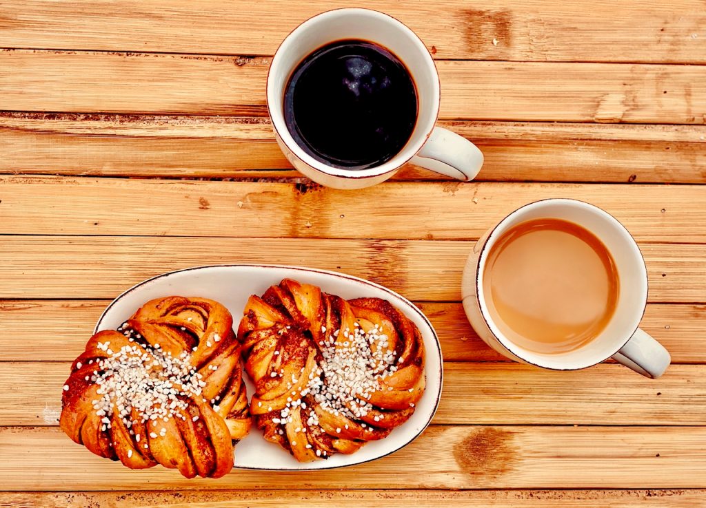 Coffee mugs and cinnamon rolls on a wooden table. Photo by Mihaela Limberea.