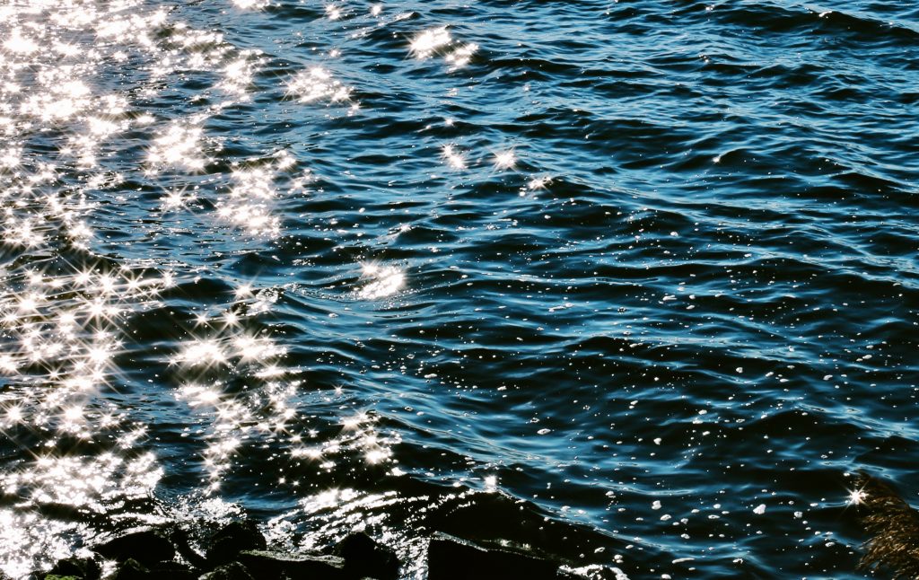 Close up of sun rays playing on dark sea waves. Photo by Mihaela Limberea