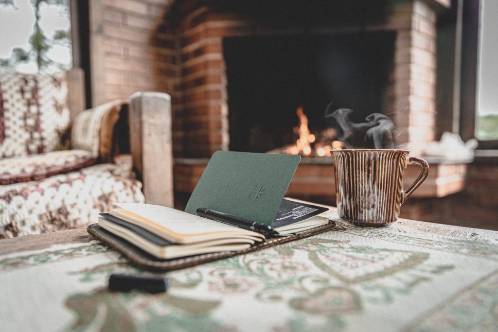 Coffee mug and notebook on a low table in front of a fireplace