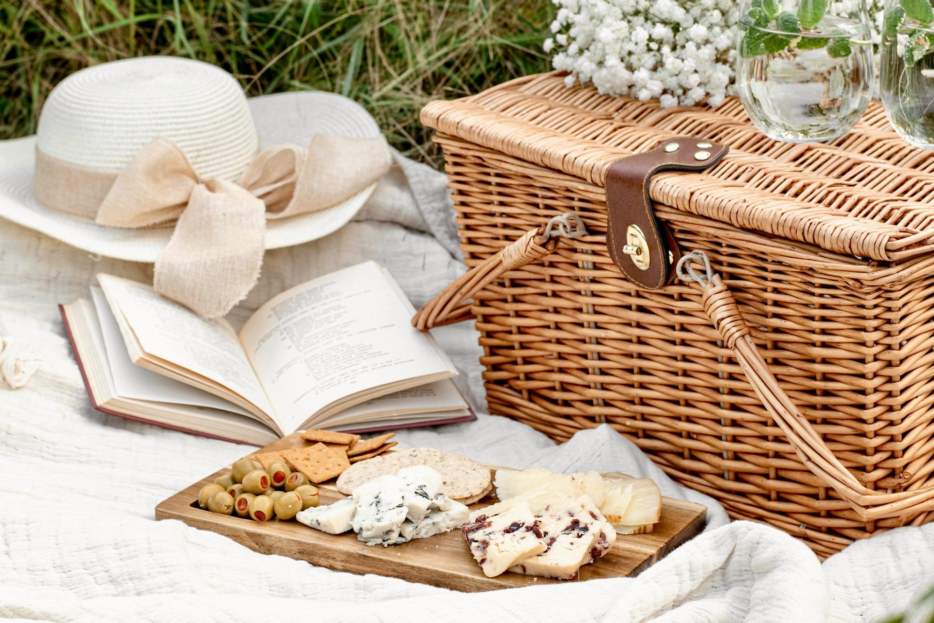 Close-up of a picnic blanket with wicker basket, hat and food
