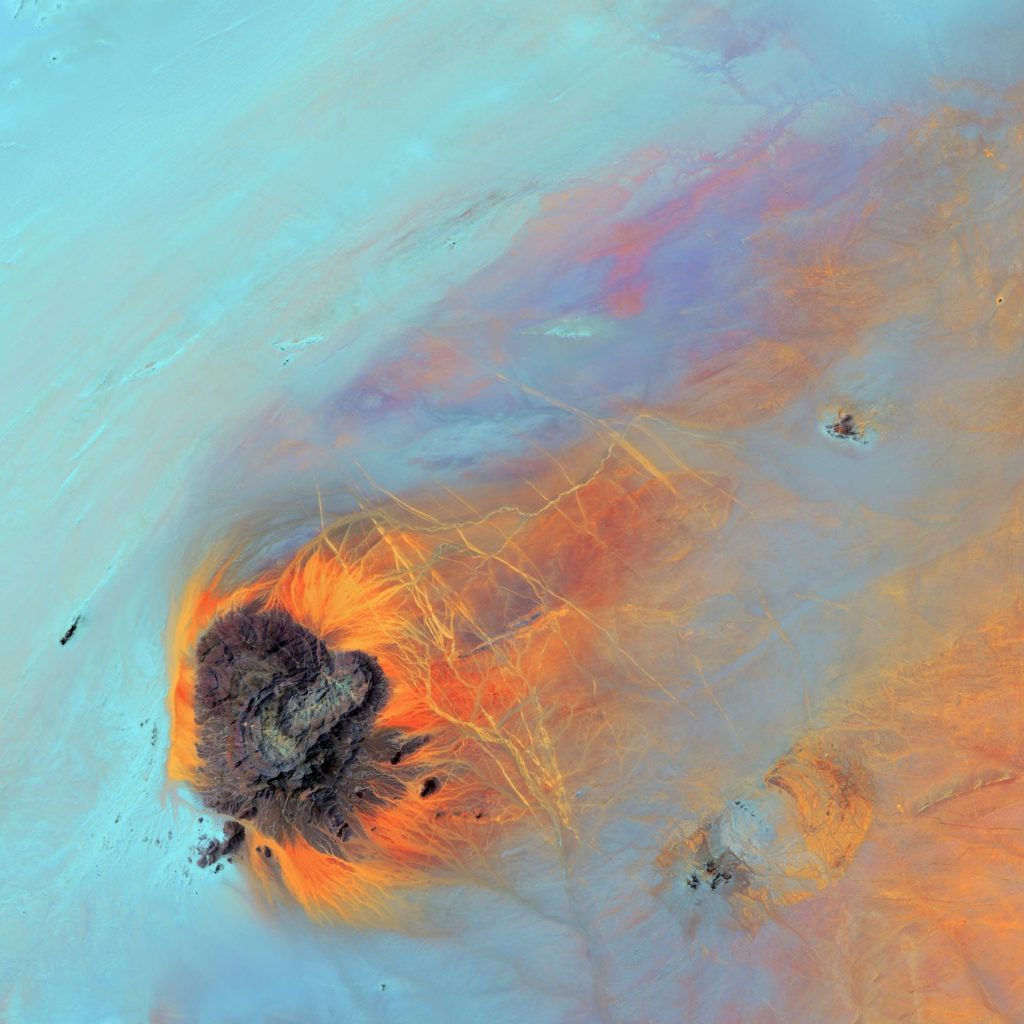 Jebel Kissu, in northwestern Sudan, emerges abruptly like an island in the vast Sahara Desert. The plateau is the eroded remnant of a granite dome. The bright linear features are truck tracks, common in the Sahara where there are no paved roads.