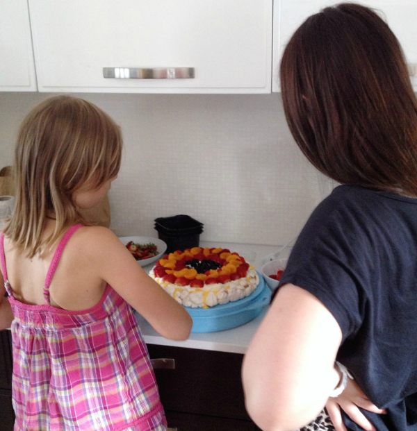 to jenter pynter pavlova kake ed frukt og bær