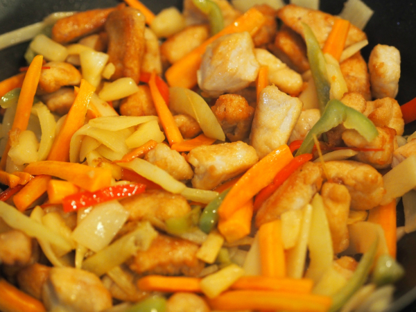 Bilde av grønnsaker og kylling blandet, klar for å helle over sausen til kylling i sursøt saus