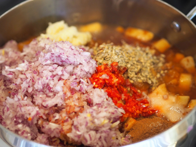 Alle ingrediense til plommechutney i en kjele.