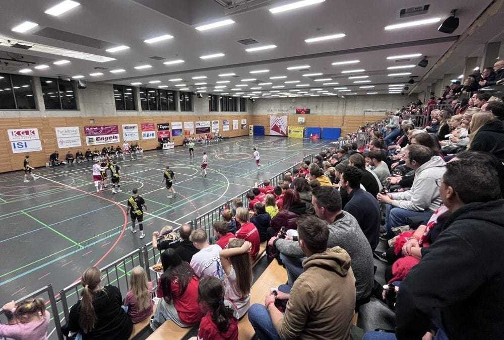 Innenaufnahme eines übersichtlichen Sporthallen-Basketballspiels mit begeisterter Zuschauerschaft auf den Tribünen, gut beleuchteter, moderner Mehrzweckhalle in lindweiler, sport, teams, fans.