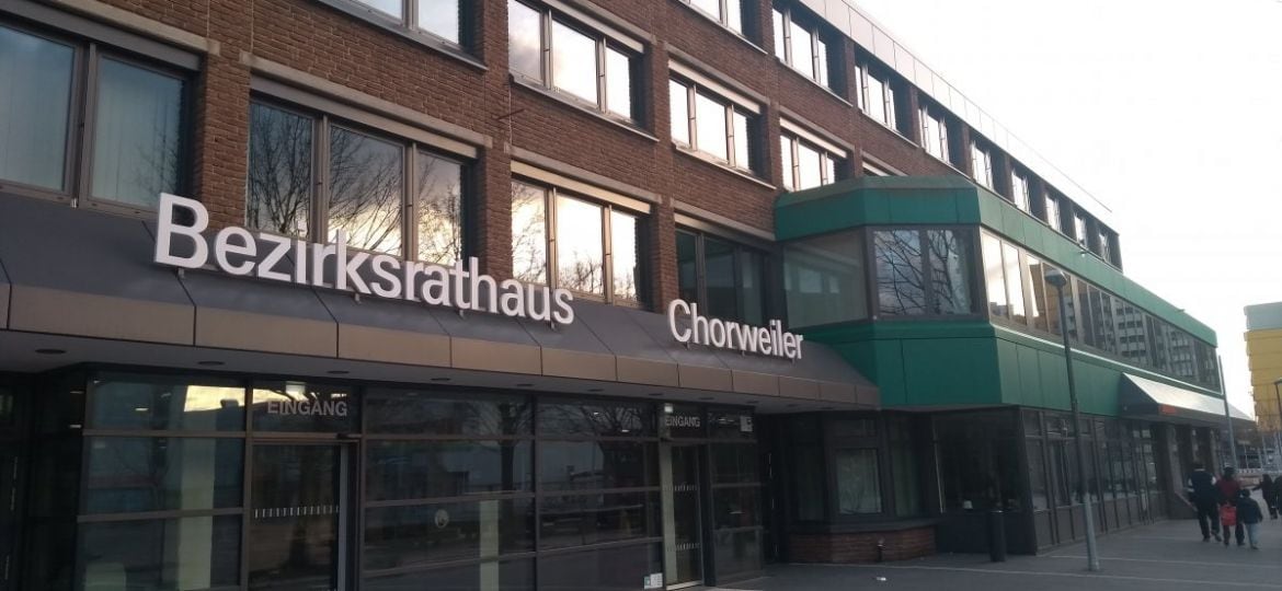 Bezirksamt Lindweiler in modernem Gebäude mit transparenten Glasfassaden und Hinweisschildern, Gebäudefront mit Fokus auf offizielle Verwaltungsstätte in Lindweiler.