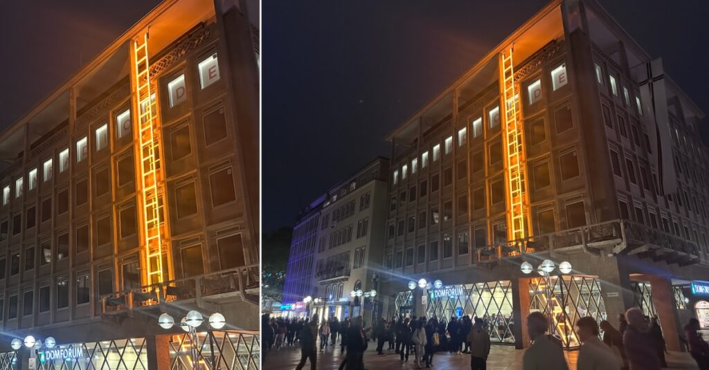 Leuchtreklame an Mehrfamilienhaus in Lindweiler bei Nacht.