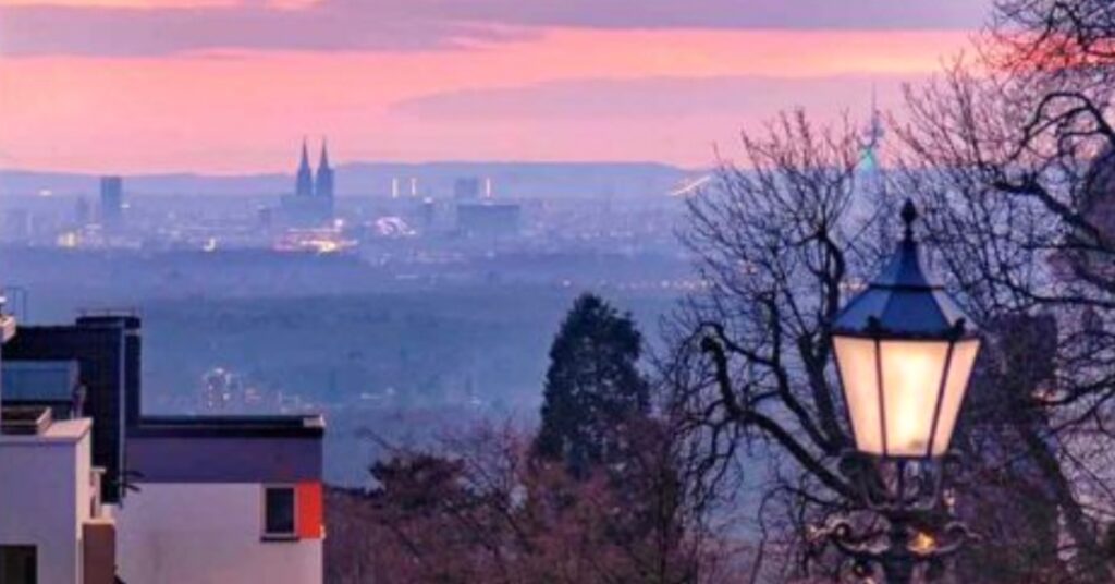 Lindweiler, Blick auf die Stadt bei Sonnenuntergang mit Lampen und Bäumen im Vordergrund.