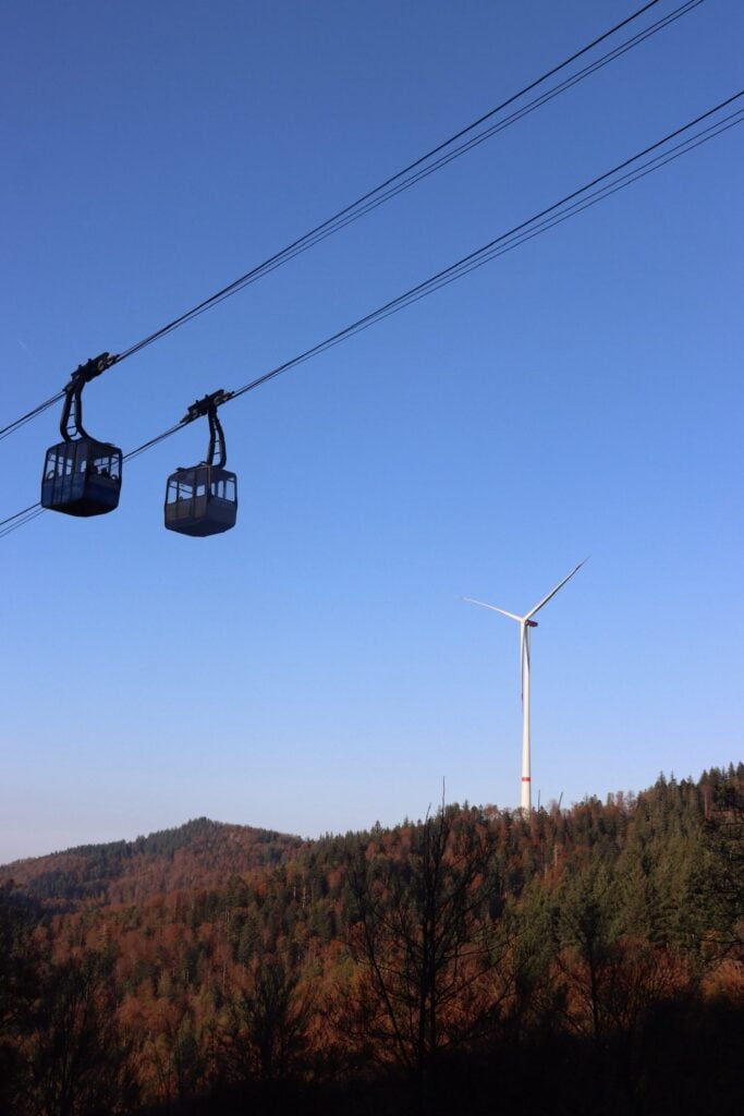 Lindweiler, Blick auf die Seilbahn und einen Windkraftgenerator im Naturpark, umgeben von Herbstwäldern, zeigt nachhaltige Infrastruktur und die malerische Landschaft der Region.