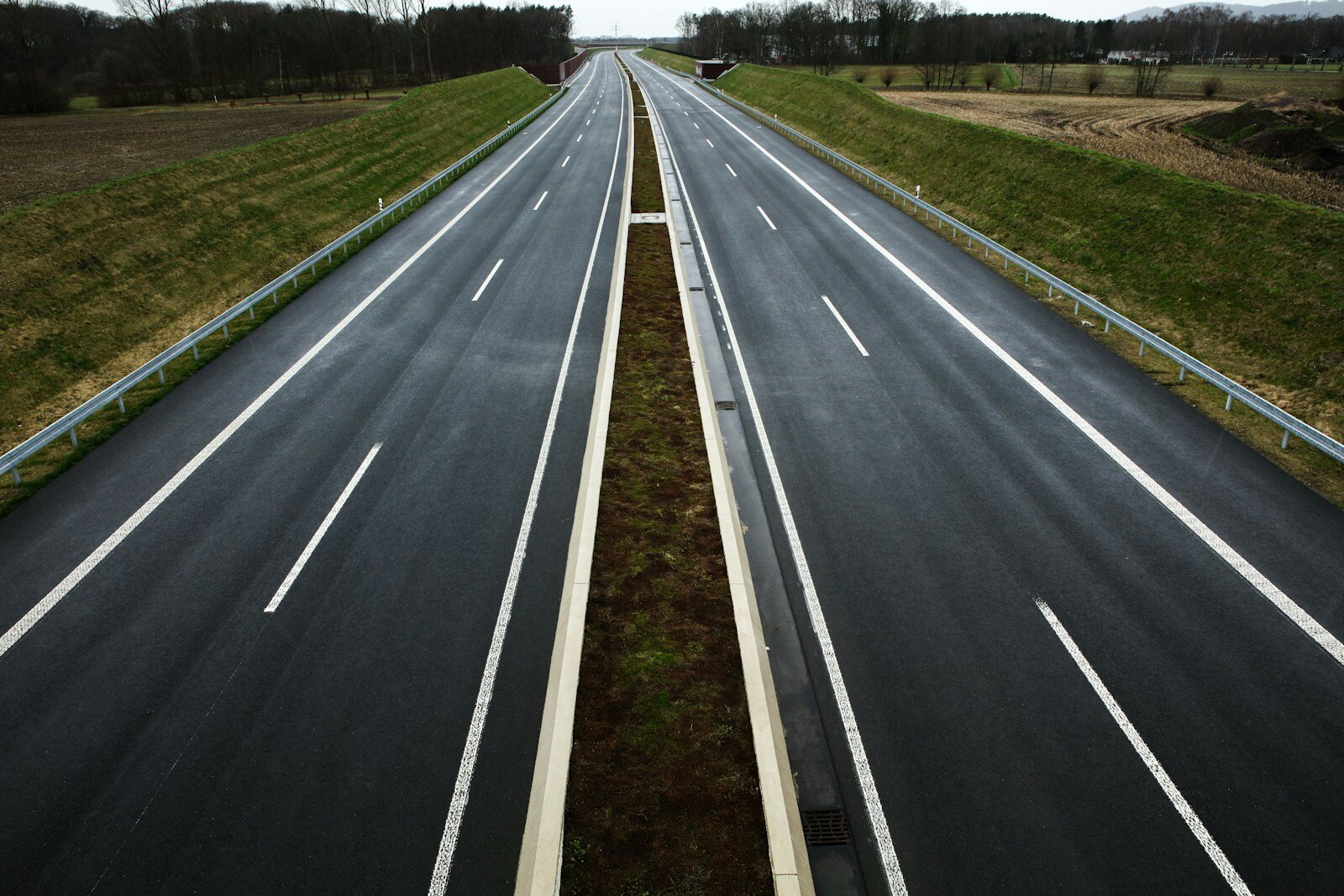 Leere Autobahn in ländlicher Gegend, asphaltierte Straßen mit Markierungen, grüne Nebenflächen, Wolkenverhangener Himmel, modernes Straßendesign, ruhige ländliche Umgebung, Lindweiler, Deutschland.