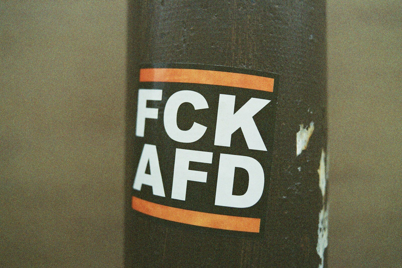 Verbotsschild mit schwarzem Hintergrund und weißen Buchstaben, inklusive orangefarbenen Balken oben und unten.