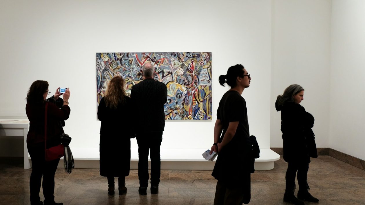 a group of people standing in front of a painting
