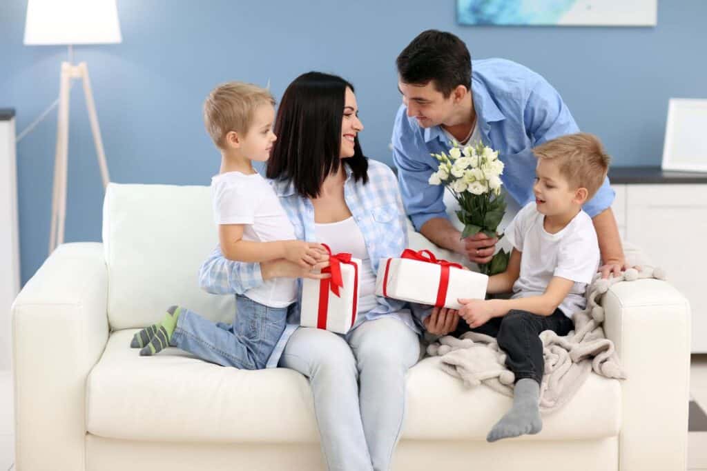 Pappa och två barn firar mamma på mors dag med att ge blommor och två paket