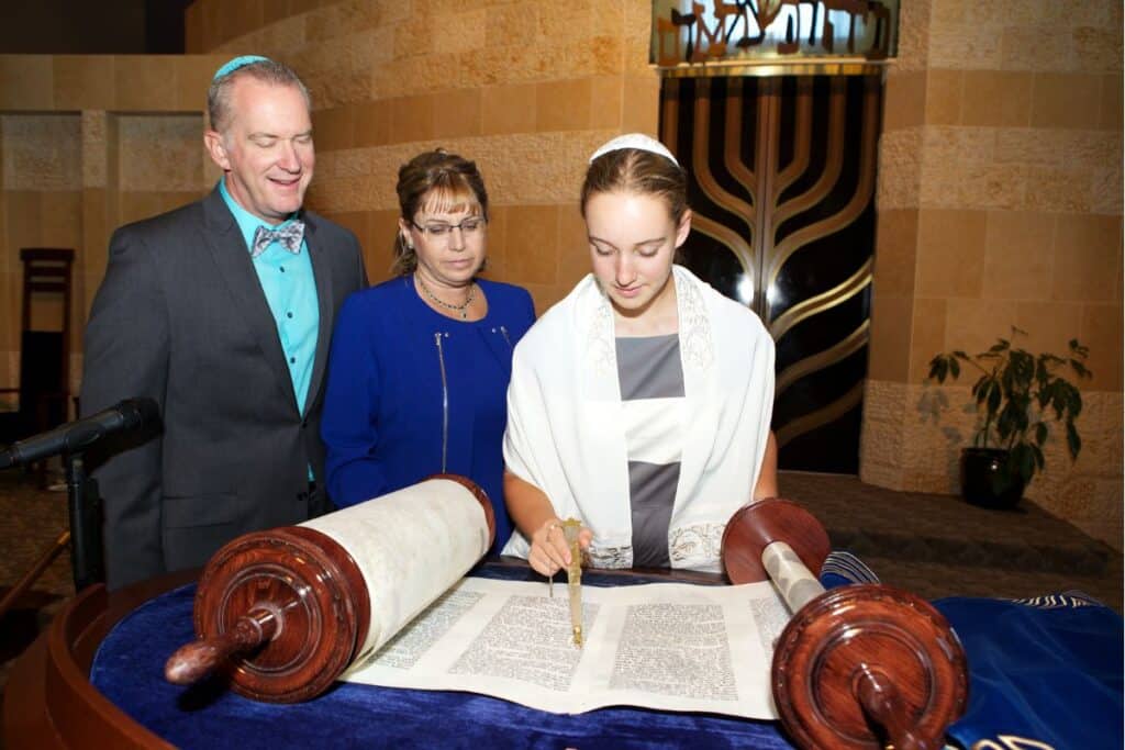 12-årig flicka läser ur Torah-rulle tillsammans med sina föräldrar i synagoga