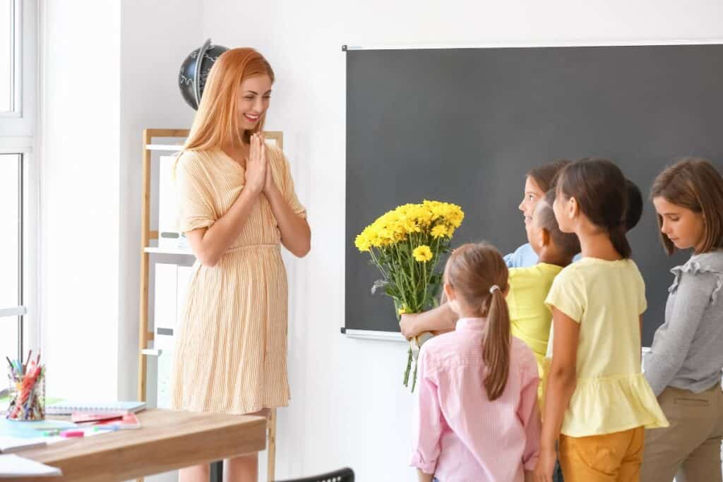 Lärare får blommor av fem av sina elever på skolavslutning i klassrum