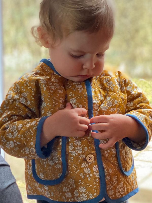 Et barn er ved at knappe sin gule quiltede jakke