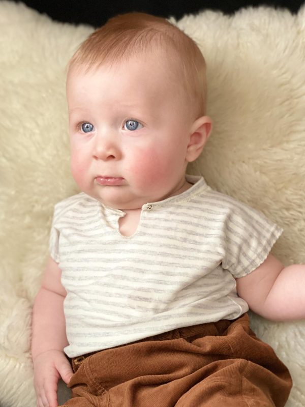 Baby med stribet bluse på et lammeskind