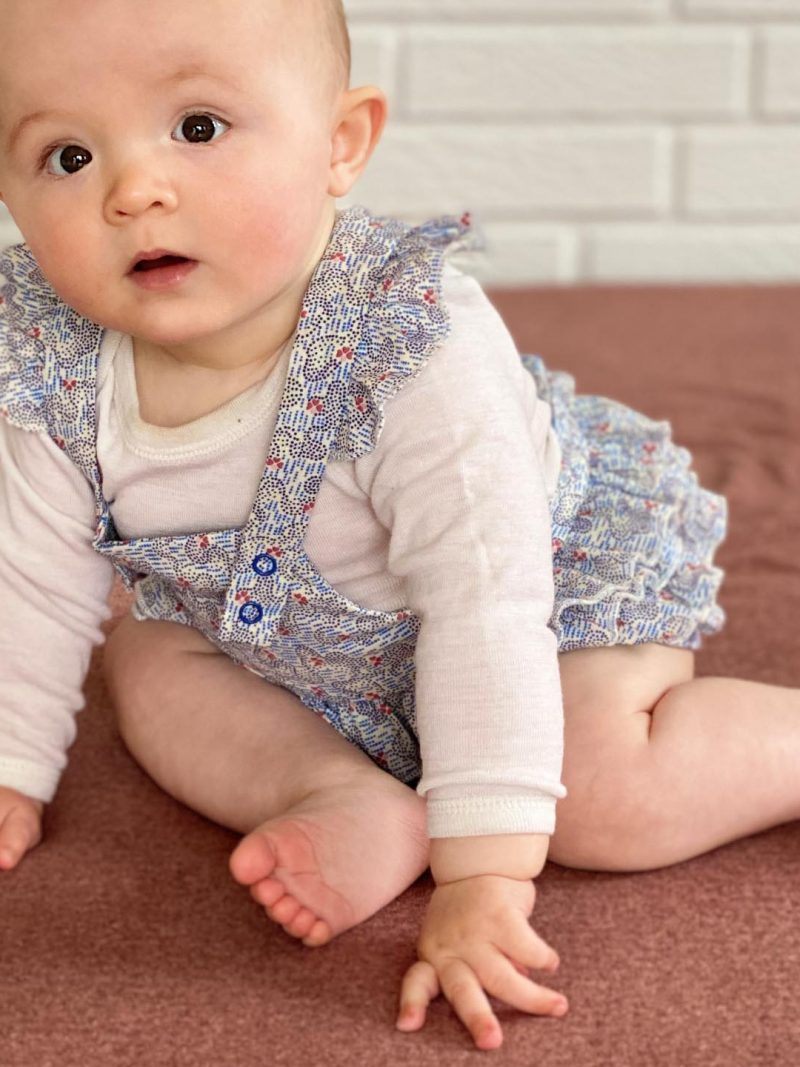 Baby i lyseblå flaesedragt på roed madras