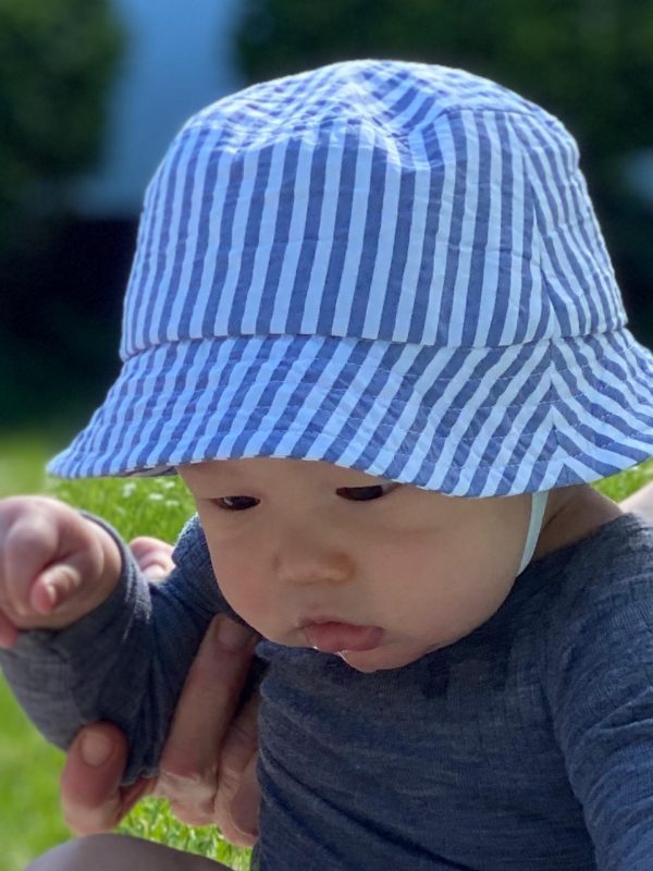 Baby med blåstribet boellehat på græsplæne