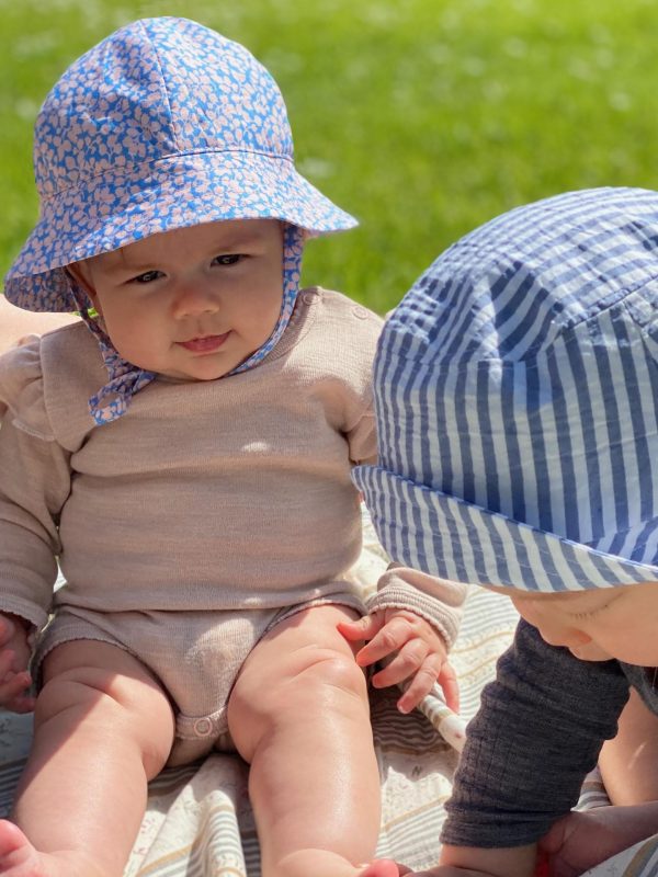 2 babyer på en græsplæne med bøllehatte