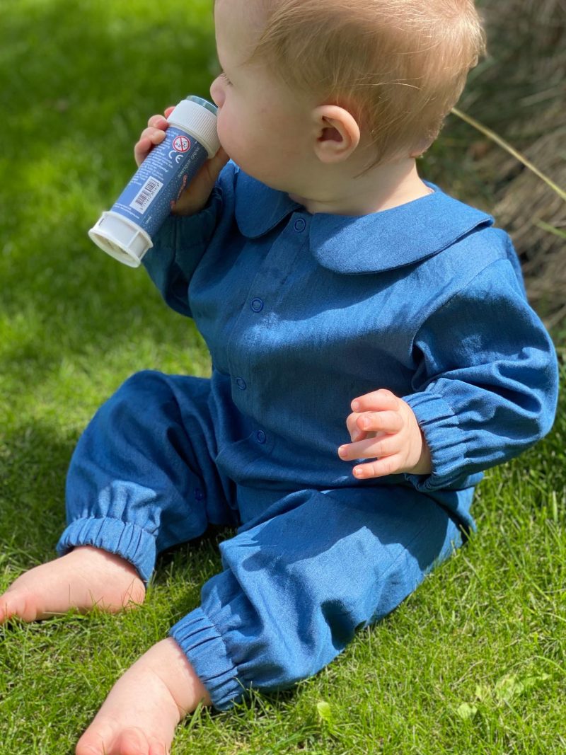 Baby i blå dragt på græsplæne