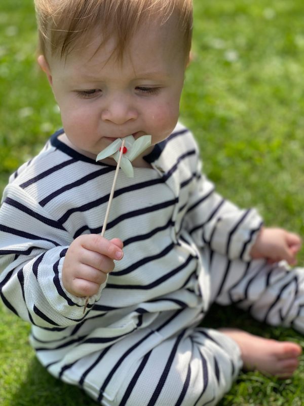 Baby med hvid og blå stribet dragt på græsplæne