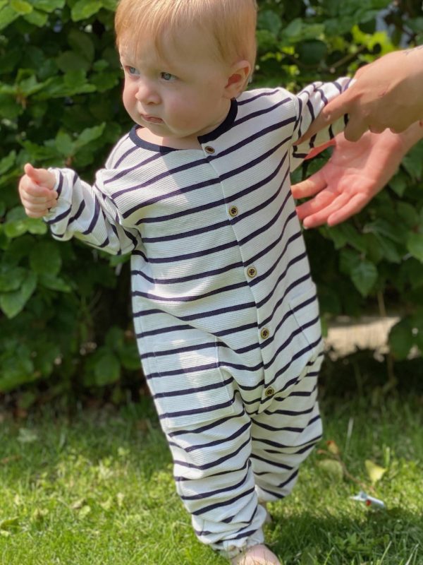Baby i blå og hvid stribet dragt på græsplæne