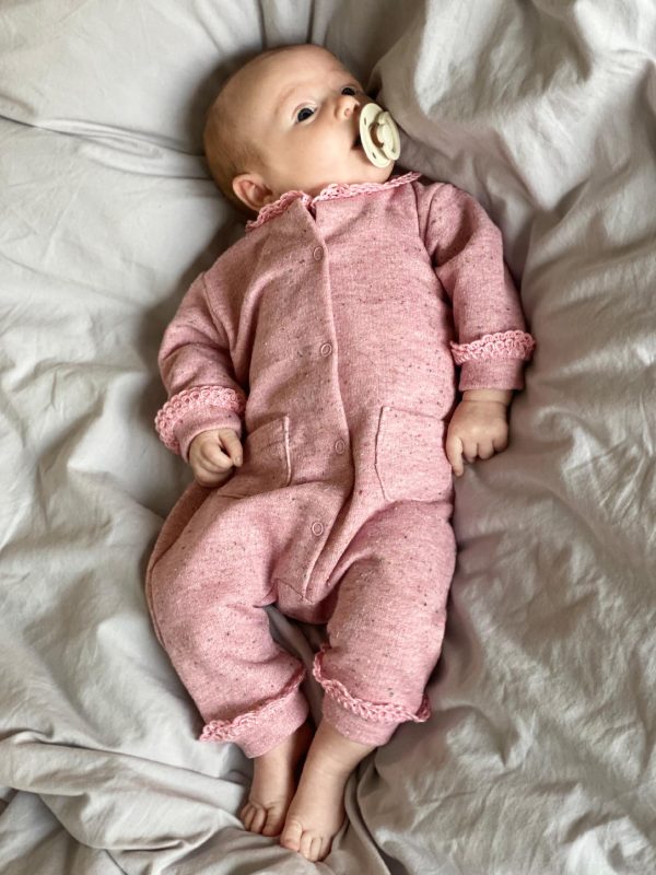 Baby i lyserød dragtr med flæser og sut