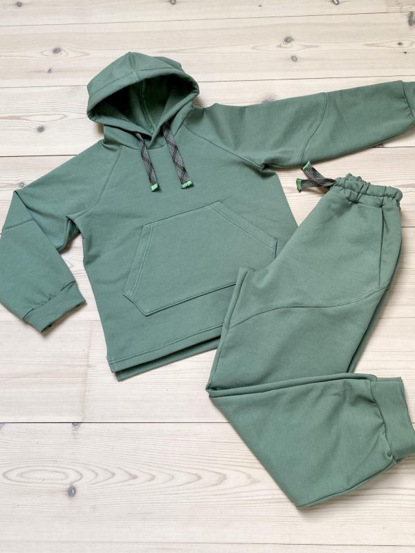Green sweat suit with hood and pocket on a wooden floor