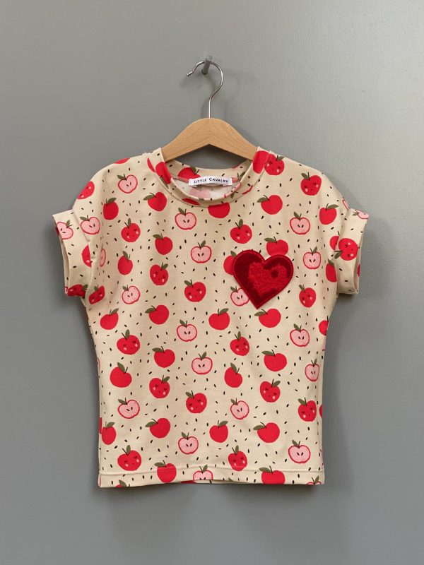 Top with red apples printed on it and a badge on the chest depicting a heart
