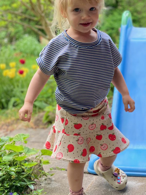 Girl with blue striped T-shirt and printed skirt with red apples
