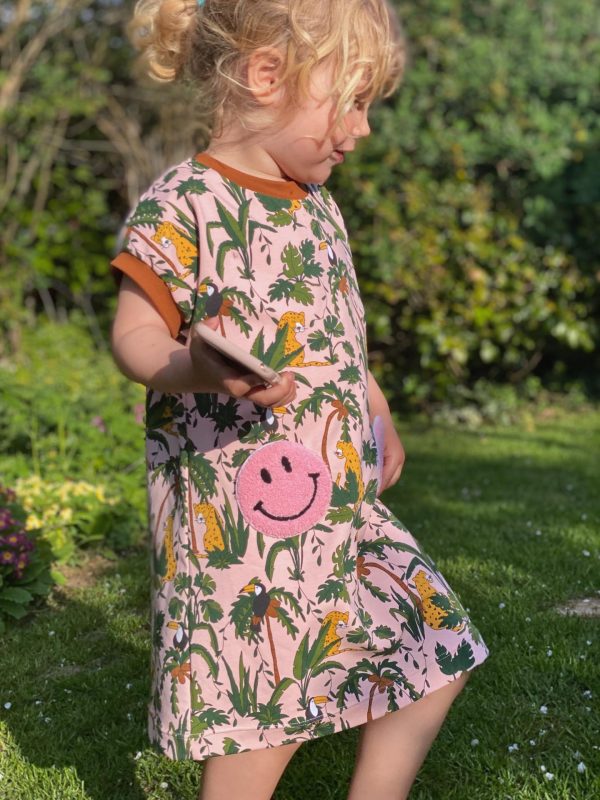 Pige i kjole med printet jersey stof og lyserøde lommer